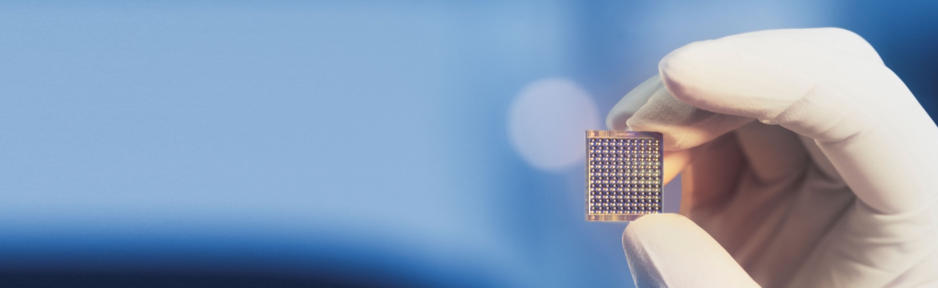 Close-up of a hand holding an INGENERIC microlens array with light sparks in the background.